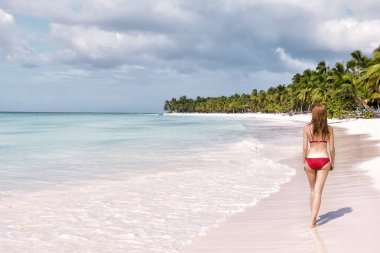 Okyanus tarafından tropikal plaj oturan güzel genç kadın