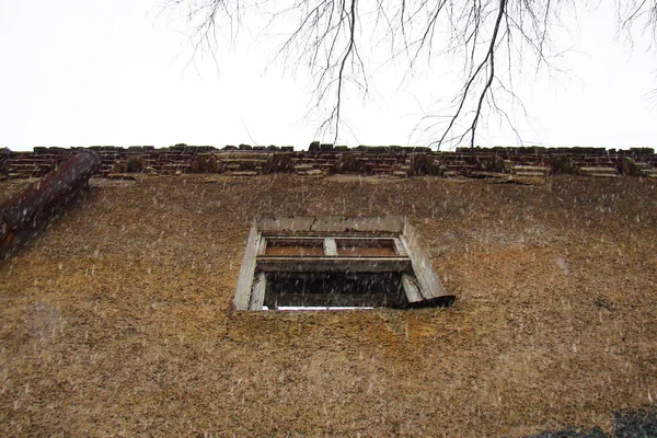 Een raam in de muur van een oud geruïneerd huis. — Stockfoto