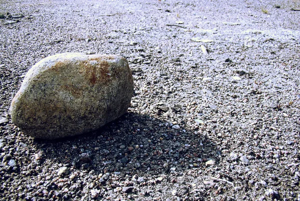 Una piedra gris solitaria proyecta una sombra . — Foto de Stock