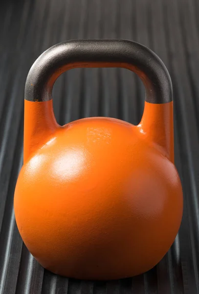 Kettlebell naranja de entrenamiento con pesas en una colchoneta de gimnasio — Foto de Stock