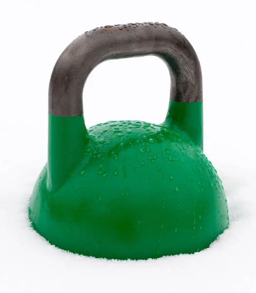 Kettlebell de entrenamiento de peso verde cubierto con gotas de agua afuera en la nieve — Foto de Stock