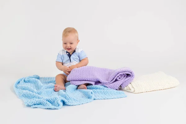 Kid with plush colored blankets on the white background