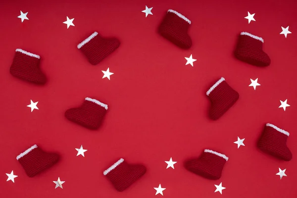 Rámeček s červeným háčkem Santa boty a jiskřivé stříbrné hvězdy na červené. Vánoční koncept — Stock fotografie