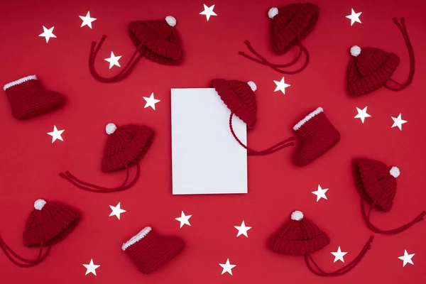 Düz bir kartpostal, kırmızı şapka, Noel Baba botları, kırmızı şapkalar ve kırmızı arka planda parlak yıldızlar. Noel konsepti — Stok fotoğraf