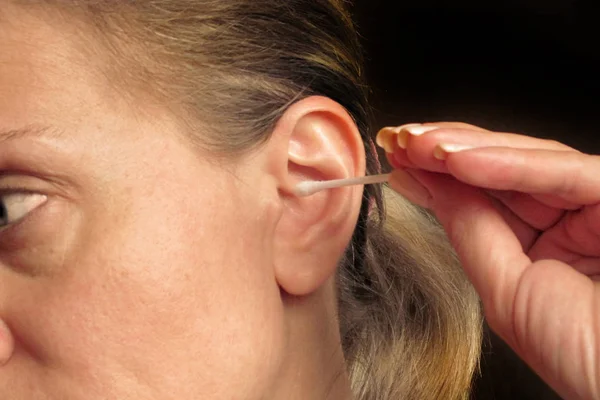 Wanita paruh baya membersihkan telinganya dengan kapas atau tongkat — Stok Foto