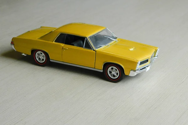 Coche de juguete amarillo en superficie rayada gris. Modelo de músculo clásico — Foto de Stock