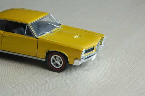 Carro de brinquedo amarelo na superfície listrada cinza. Modelo de músculo clássico — Fotografia de Stock