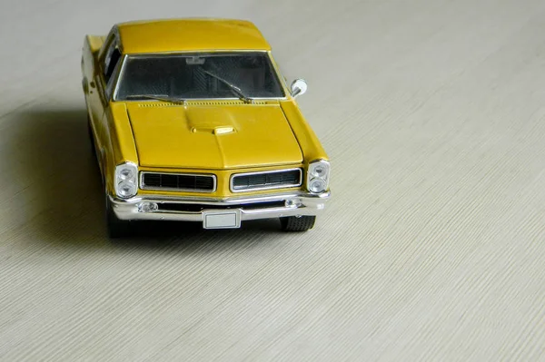 Carro de brinquedo amarelo na superfície listrada cinza. Modelo de músculo clássico — Fotografia de Stock