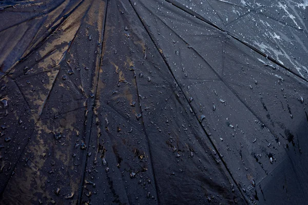 Wet black umbrella close up image. Waterproof fabric cloth with