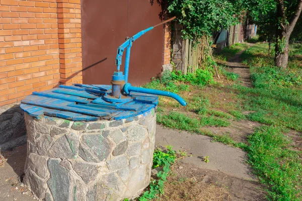 Çiftlik köyü ilçe su iyi el manuel pompa ile. Eski kamu hizmetleri tedarik tesisleri. Ülke yaşam tarzı imajı. İçme suyu teslimi veya tedarikinin ilkel mekanizması