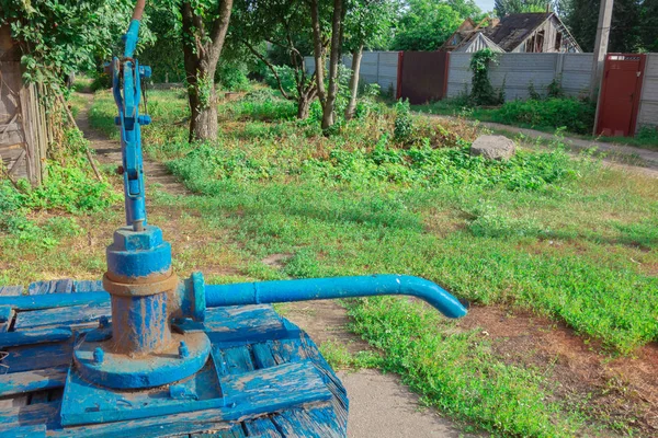 Farm village county water well with hand manual pump. Old utility supply facilities. Country lifestyle image. Primitive mechanism of delivery or supply of drinking water