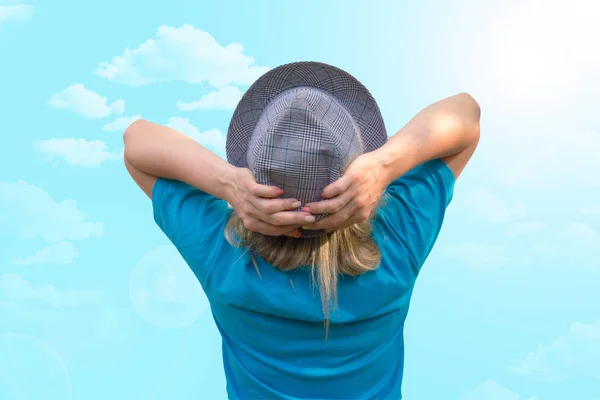 Şapkalı kız. Beyaz orta yaşlı kadın bize geri kalır ve ellerini başının arkasına koyar. Yüz olmadan arka görünüm