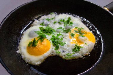 Dökme demir kızartma tavası maydanoz dekorasyon uğrama ile kızarmış yumurta kadar Sunny tarafı. Protein beslenmesi ile ev yapımı mutfak veya sağlıklı gıda kavramı. İzole arka planda görüntüyü kapatma