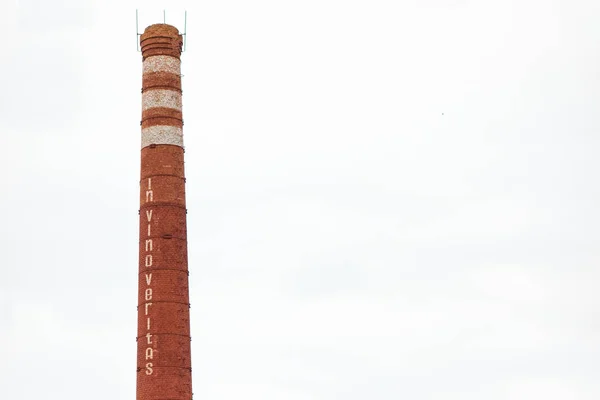 インヴィーノベリタスのテキストとワインボトルネックの形の煙突 孤立した背景に産業煙突 アルコール飲料のコンセプトの製造 ローマ帝国のラテン語引用 — ストック写真