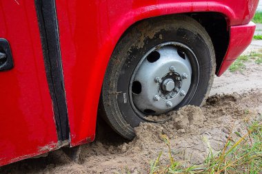 Kharkiv, Ukrayna, Ağustos, 2019 Otobüs tekerleği kuma saplanmış. Kırmızı büyük araba çamura saplanmış. Asfaltsız yolda trafik sorunu. Kirli lastik ve partiküllü araç tarafı