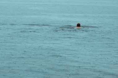 Adam yağmur altında yüzer. R arasında suda yüzme adam Başkanı