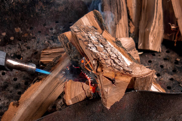 Fireplace kindling of chopped wood logs by gas torch. Method of 