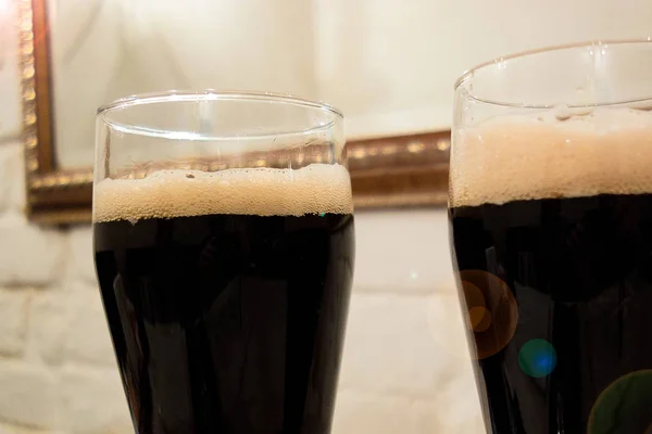 Два стакана темного пива или безалкогольного напитка с пеной на голове . — стоковое фото
