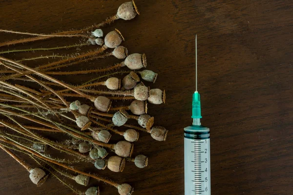 Haşhaş kapsülleri yığını ve koyu arka plan üzerinde şırınga makro kullanılır. Uyuşturucu