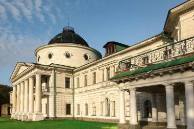 Mavi gökyüzünde levrek ve sütunları olan eski bina cephesi.