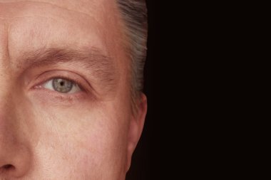 Yetişkin bir adamın yarı yüzü koyu arkaplanda fotokopi alanı ile yakın plan