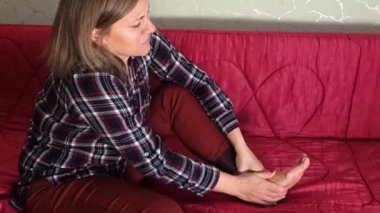 Kadın ayağına negatif duygularla masaj yapıyor. Orta yaşlı ya da yaşlı beyaz kadın acılarını azaltmak için ayak topuğunu ve parmaklarını ovar. Mutsuz.