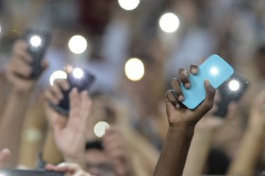 Flaş ile bir cep telefonu tutan kişi ve eller yukarı