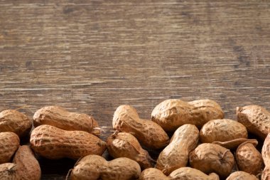 Kabuktaki bir sıra fıstık kahverengi arka planda sınır oluşturuyor, üst görünümde ise metin kopyası var. Haziran partilerindeki tipik yiyecekler (Festa Junina)