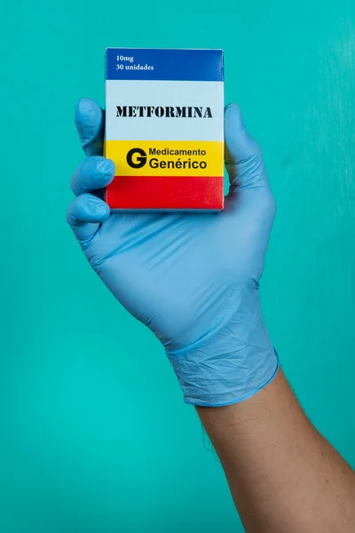 Doktorun elinde yeşil arka planda koruyucu eldivenlerle (kutuda yazılı) metformin ilacı kutusu var