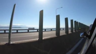 Rio-Niteroi köprüsünün merkezi yol manzarası bir arabanın yan tarafından, bir kısmı ise yan tarafından görünüyor.