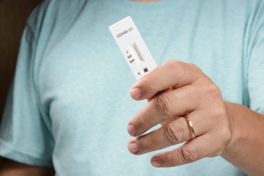 Adamın elinde covid-19 negatif test kiti var.