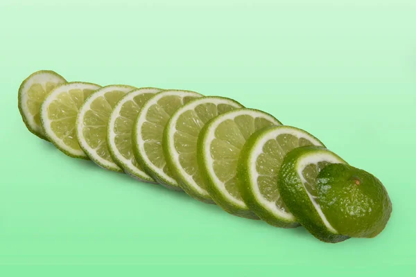 Tahitian lemon cut into slices on light green background