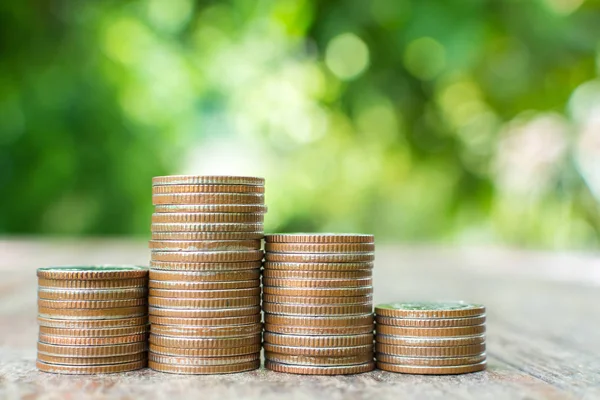 Moneta pila su tavolo in legno con sfondo sfocato foglia verde, Risparmiare denaro e concetto di investimento — Foto Stock