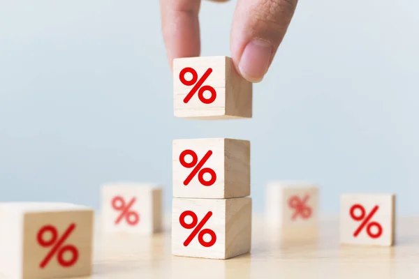 Interest rate financial and mortgage rates concept. Hand putting wood cube block increasing on top with icon percentage symbol upward direction