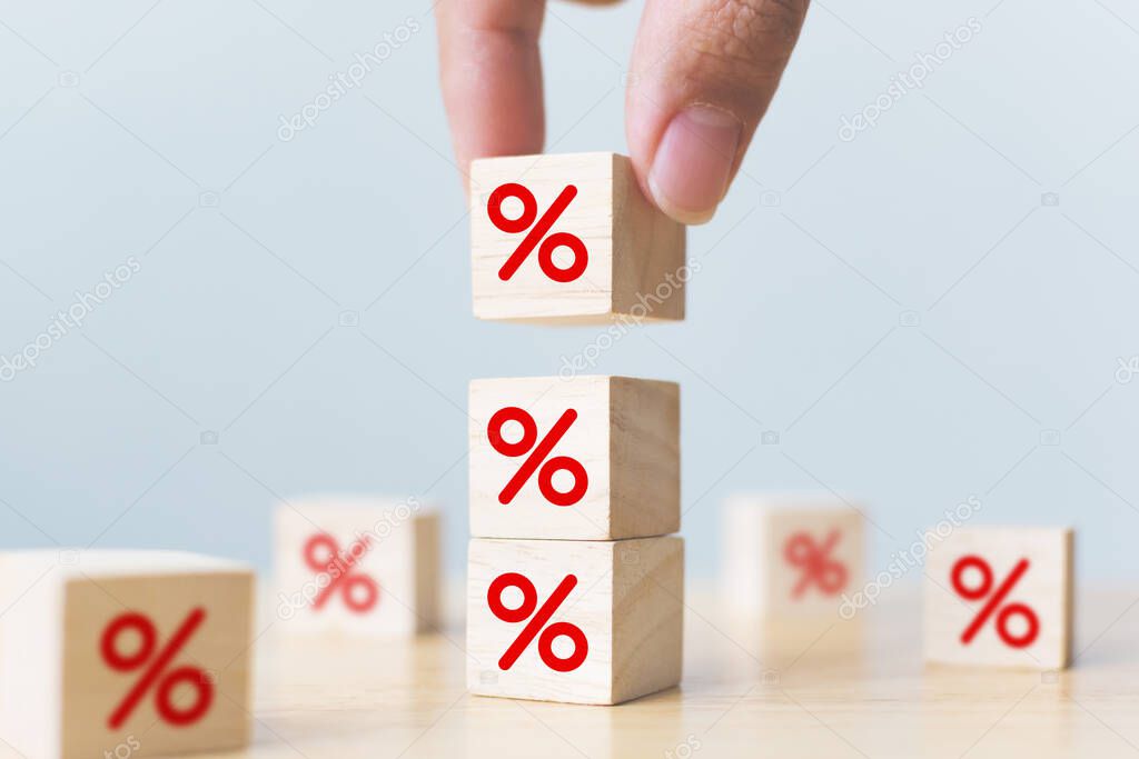 Interest rate financial and mortgage rates concept. Hand putting wood cube block increasing on top with icon percentage symbol upward direction