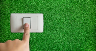 Enerji tasarrufu verimliliği kavramı. Çimen arka planlı el kapatma düğmesi