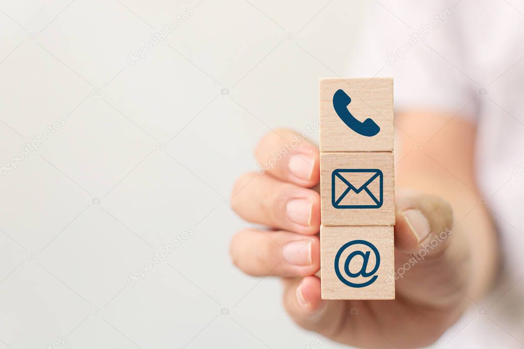 Hand holding wooden block cube symbol telephone, email, address. Website page contact us or e-mail marketing concept