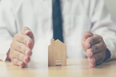 Sigorta ev koruması konsepti. Erkek eli ahşap evi engeller
