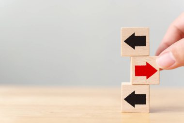 El ele tutuşan ahşap blok ve kırmızı ok ters yöne bakan siyah oklar, Eşsiz, farklı düşün, bireysel ve kalabalığın konseptinden uzak dur