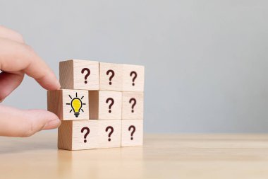 Yaratıcı fikir ve yenilik kavramı. İnsan sembolü, ampul simgesi ve soru işareti sembolü olan tahta bloğu elle seçtik.