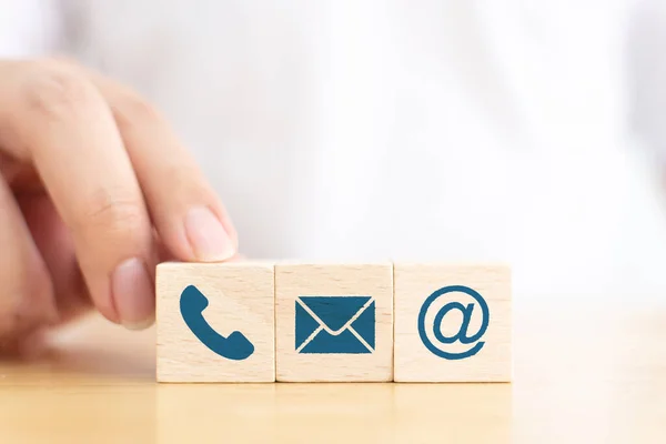 İşadamı eliyle tahta blok küp simgesi ikon telefon, zarf e-posta ve adres levhasını seçti. Web sitesi bizimle ya da e-posta pazarlama konseptiyle iletişime geçin