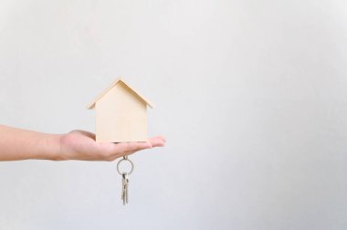 Elle tutulan ahşap ev ve ev anahtarlığı. Emlak yatırımı ve konut kredisi finansal emlak kavramı