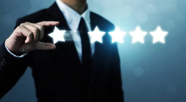 Şirket konseptini yükseltmek için iş adamı elinde beş yıldızlı sembol tutuyor