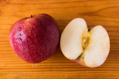 bir kırmızı elma ve ahşap kahverengi bir tahta üzerinde başka bir elma parçası, bir elma, doku, arka plan, yakın çekim, meyve su damlaları