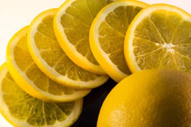 beyaz backg izole siyah bir tabak üzerinde portakal ve limon dilimleri