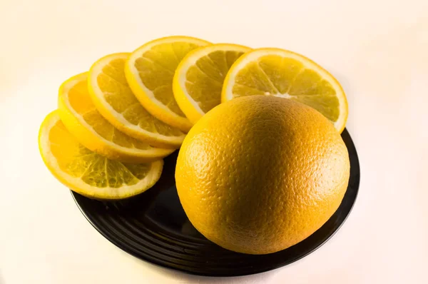 Orange and lemon slices on a black plate on white backgrond — Stock Photo, Image