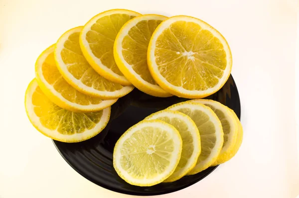 Rodajas de naranja y limón en un plato negro aislado sobre fondo blanco — Foto de Stock