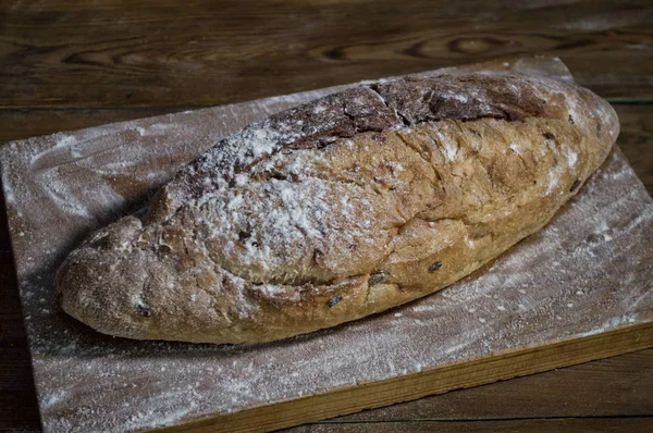 Fresh bread on a kitchen board in flour. Wooden background, top — Stock Photo, Image