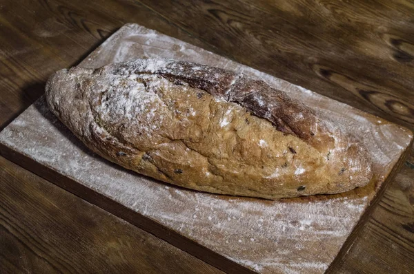 Fresh bread on a kitchen board in flour. Wooden background, top — Stock Photo, Image