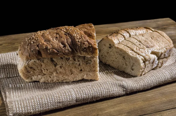 Fresh sliced wheat bran bread on wooden table. Baking compositio — Stock Photo, Image